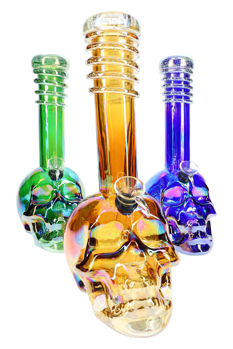 Trio of 10.5-inch metallic skull glass bongs in green, amber, and purple rainbow finish with ribbed glow necks arranged on white backdrop.