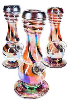 Group of three 7.5-inch metallic stripe beaker bongs in assorted rainbow hues with ribbed neck grips, reflective soft-glass bases, and grommet bowls on white background.