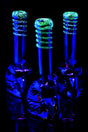 Metallic eagle water pipes glowing bright green frit rings under UV light, showcasing reflective bases in dark room.