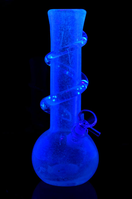 UV-reactive soft glass round-base water pipe glowing under blacklight; illuminated clear spiral grip accents along the neck.