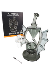 Nocturne mini dab rig beside retail box, showing bat-wing design, quartz banger, and metal dab tool in Halloween collection packaging.