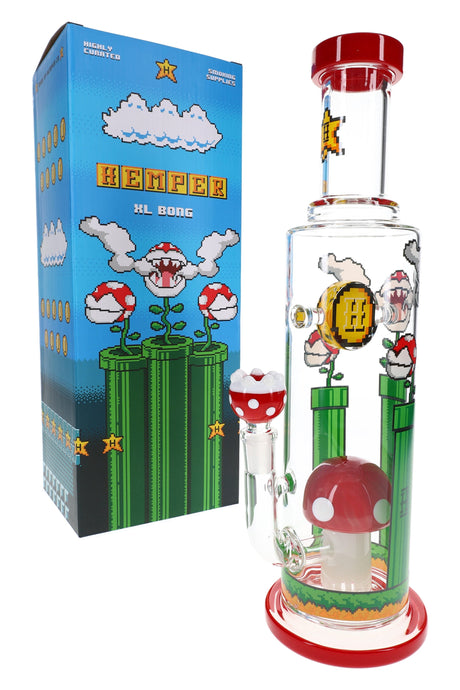 Hemper Gaming Flower XL themed glass bong standing beside blue pixel-art box, showing mushroom bowl, coin decal and tall straight-tube design.
