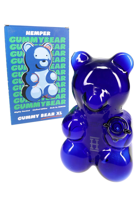 Hemper Gummy Bear XL deep blue glass water pipe next to bold blue Gummy Bear XL box, angled studio product shot on white.