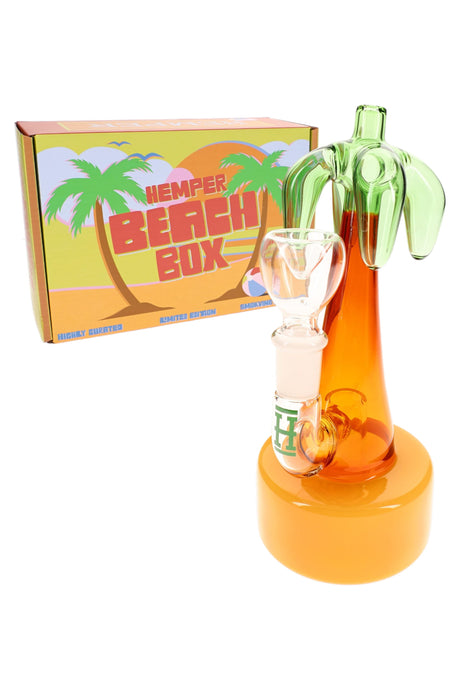 Hemper Palm Tree mini bong standing beside bright Beach Box packaging, showing tropical colors and compact 7-inch design.