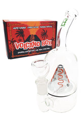 Hemper Volcano 7-inch glass bong posed in front of bright red Volcano Box packaging, showing curved neck and matching flower bowl.