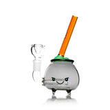 Front angle cauldron glass bong showing glow bubble top, angry face decal, and amber stirrer mouthpiece, 6″