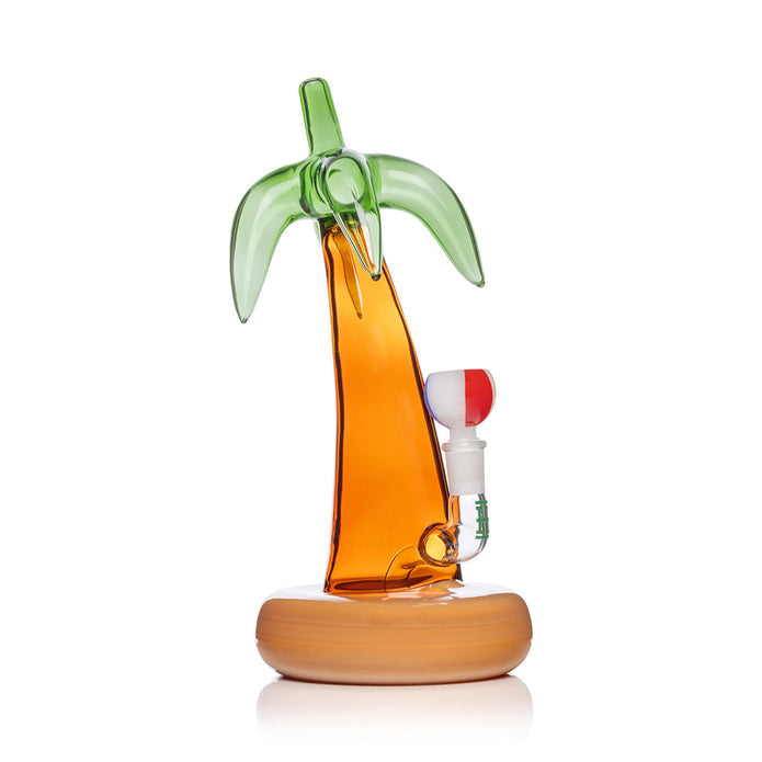 Side profile palm tree glass bong showing amber trunk, green fronds silhouette, and wide sand-colored base for stability