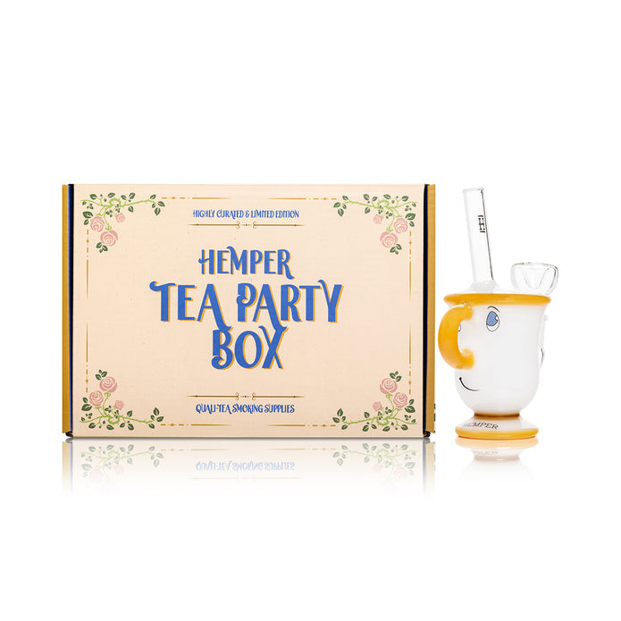 Wide shot of Hemper Tea Party Box next to tea cup glass bong, white cup body with amber accents and bowl