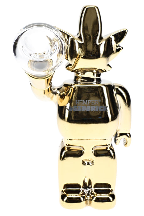 Front close-up of mirror-gold Weedbrick glass bong holding clear bowl, glossy finish and character silhouette detail