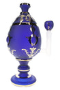 Close-up of XL jeweled egg glass bong with ornate blue body, clear stem section, and novelty display styling