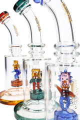 Close-up of three 6B Glass bongs showing colorful sculpted clown percs inside clear glass chambers