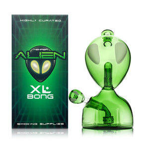 Hemper Alien XL green glass bong with oversized oval eyes and matching alien-head bowl beside its retail box