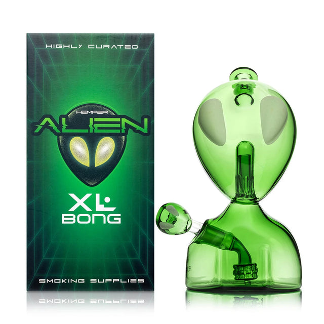 Hemper Alien XL green glass bong with oversized oval eyes and matching alien-head bowl beside its retail box