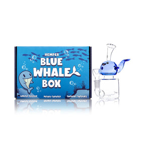 Hemper Blue Whale glass bong with a clear spout mouthpiece and bowl beside its blue illustrated retail box