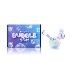 Hemper Bubble iridescent glass bong with a clear bowl beside its blue and purple illustrated retail box
