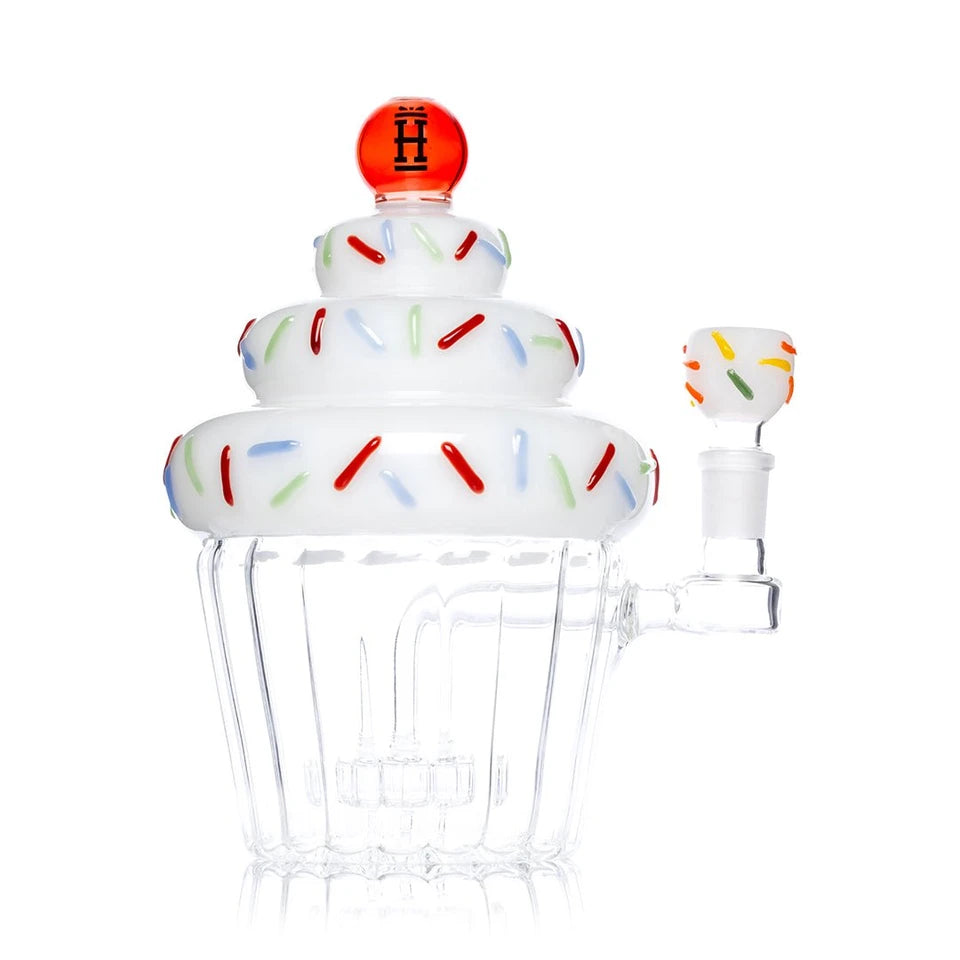 Hemper Cupcake XL bong with a red cherry topper, stacked white frosting and sprinkle-decorated bowl at right