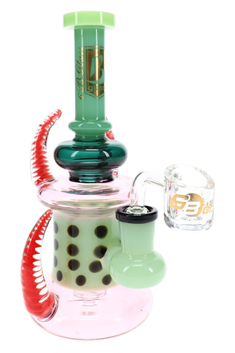 6B Glass dab rig with green neck, dotted inner chamber, red curved spikes, pink base, and clear banger.