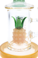 Close-up of pineapple-shaped glass percolator with raised yellow fruit details and green leaves inside a clear bong.