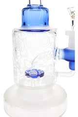 Close-up of frosted doodle graphics around a clear bong chamber with blue showerhead perc and frosted circular base.