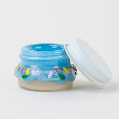 Blue donut-inspired terp jar with lid propped beside, rainbow sprinkle accents circling body, white background product shot