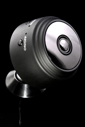 Matte black 1080p wireless mini cam on magnetic stand, side angle showing on/off button and infrared night-vision LEDs on black backdrop