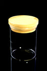 Medium glass jar with natural bamboo lid and visible silicone gasket, angled side view on reflective black surface