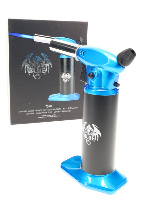 Blue Special Blue Toro torch lighter next to product box, chrome nozzle and adjustable dial visible on a clean white background.