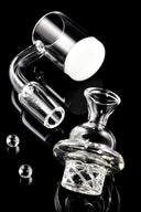 Close-up of quartz spinner banger showing white thick bottom base with turbine cap and two clear banger beads on black.