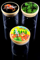 Three medium clear glass jars with bamboo pop-top lids and assorted decal art—tropical fish, cannabis leaves, cartoon scientist—on glossy black background