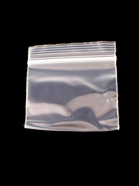 Single Apple Bags clear mini zip baggie, 2 × 2 inches, showing airtight zipper closure against glossy black backdrop