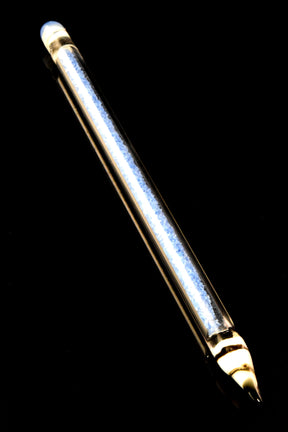 Single blue-core glass pencil dab tool with sparkling frit interior and pointed loading tip, angled on glossy black surface.