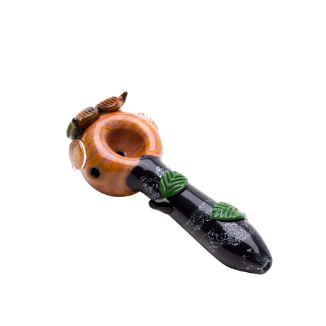 Top view of amber owl dry herb pipe with rounded bowl, green leaves, and dark branch-inspired handle