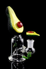 Black-background Avocadope dab rig with clear beaker base, sculpted avocado top, and pit-style bowl